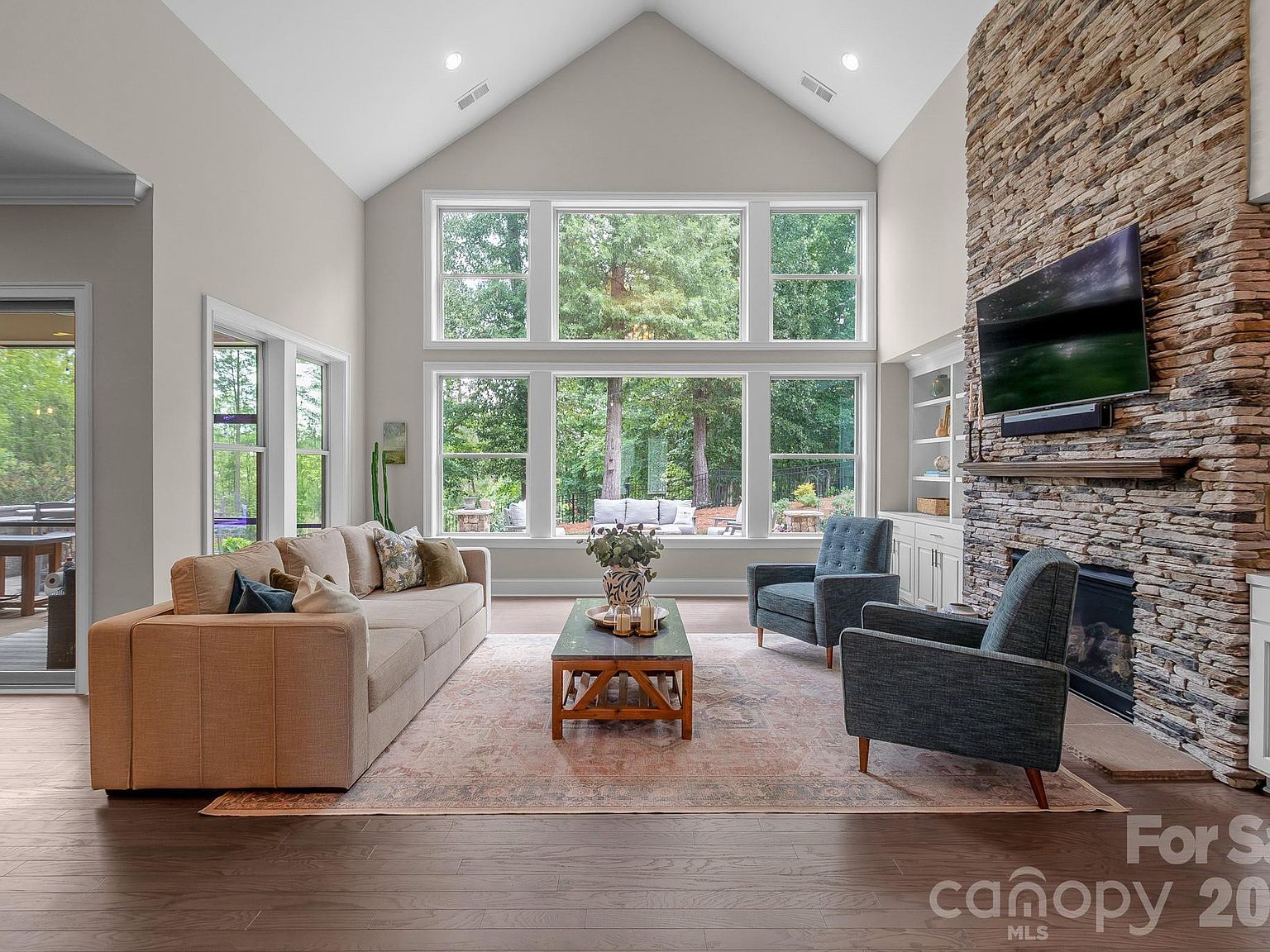 The great room from another angle: floor-to-ceiling stacked-stone fireplace flanked by custom built-ins.