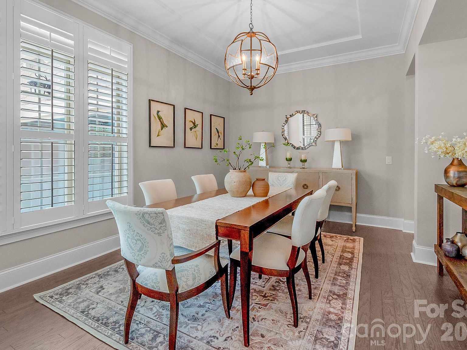 The two-story great room: vaulted ceiling, expansive windows to the wooded backyard, hardwood floors flowing into the kitchen.