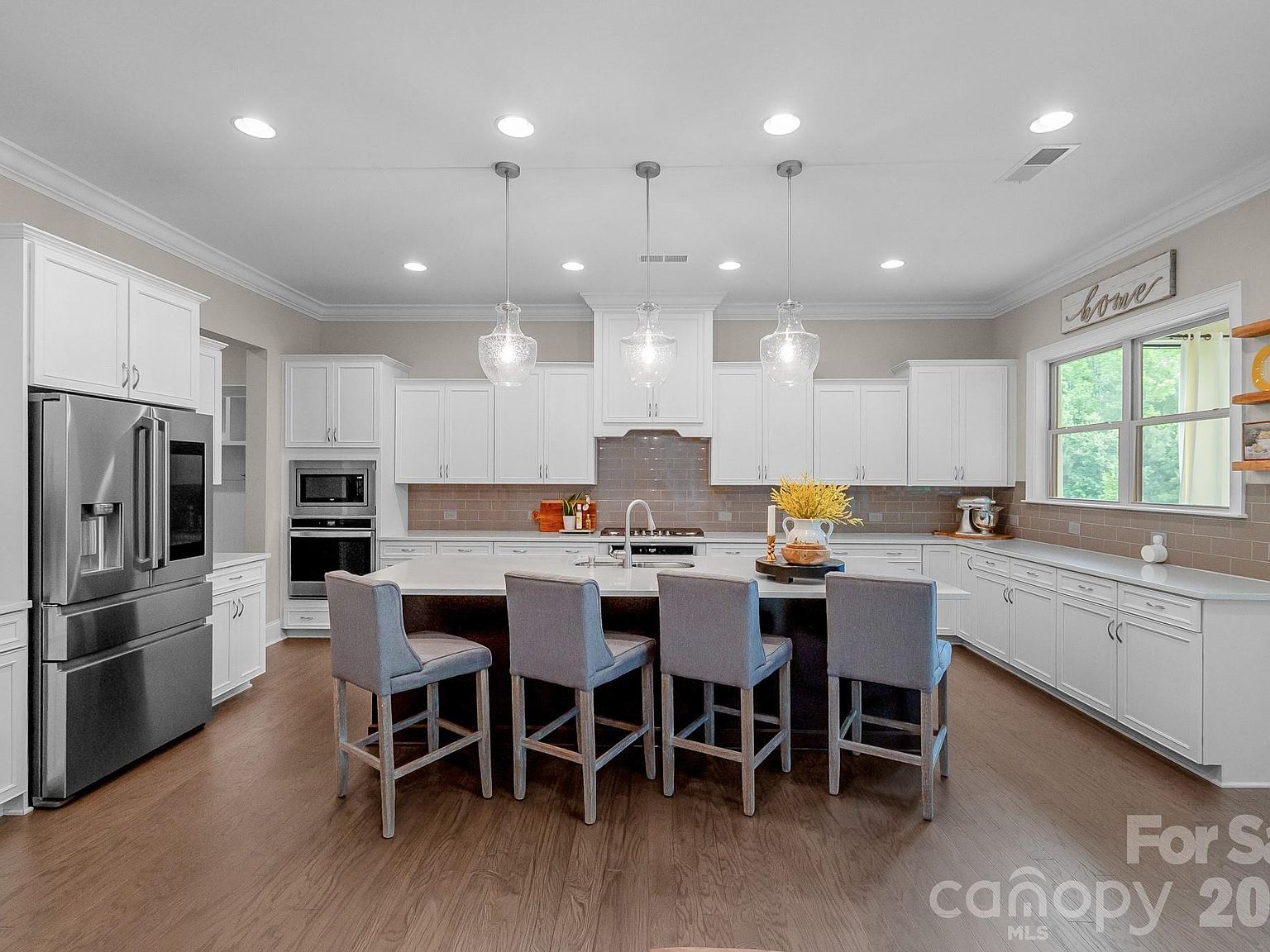 The chef's kitchen: quartz countertops, oversized island with seating for four, white shaker cabinetry and tile backsplash.