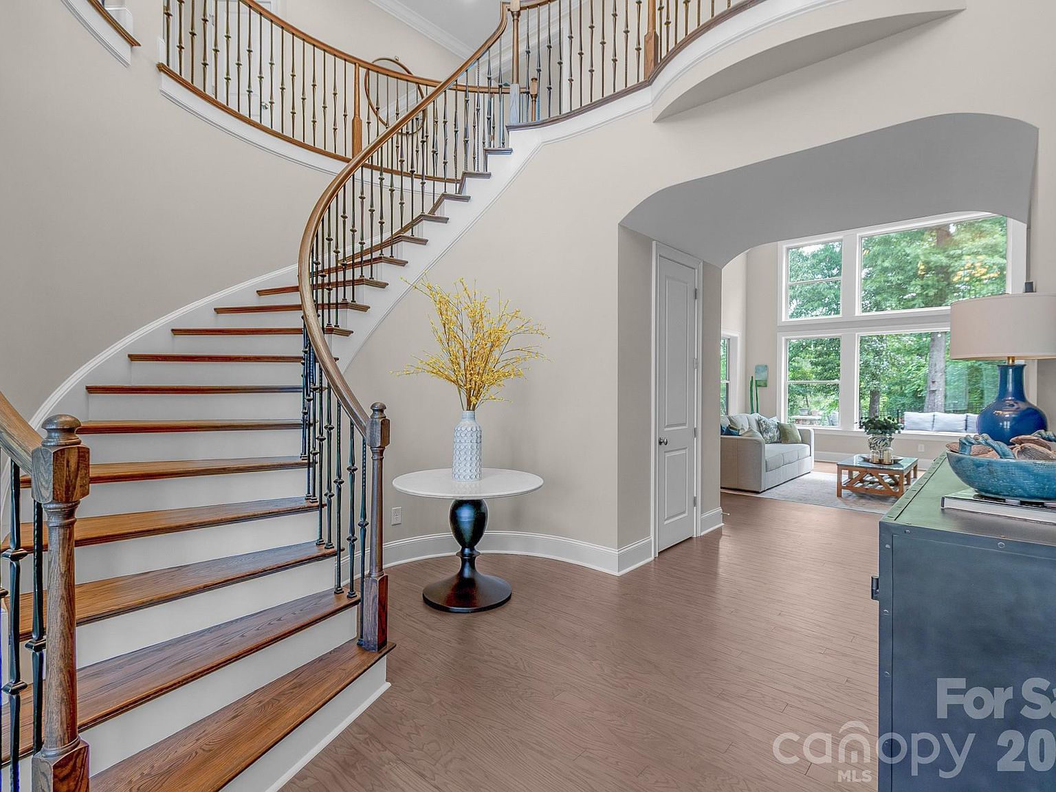The two-story foyer with a curved staircase, wrought-iron balusters, and hardwood flooring.